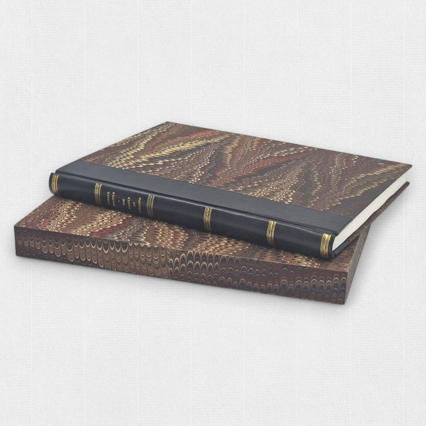 A luxurious 2022 Rambler Press edition of The Castle of Otranto by Horace Walpole, limited to 25 hand-numbered copies. The octavo book, printed on Century Laid cotton paper with watermarks in Monotype Bell typeface, features a half-leather binding with hand-marbled paper sides, gilded edges, and a custom slipcase. The cover evokes the eerie Gothic atmosphere of the 1764 novel, with shadowy castle motifs and intricate detailing, reflecting its status as the cornerstone of the Gothic genre.