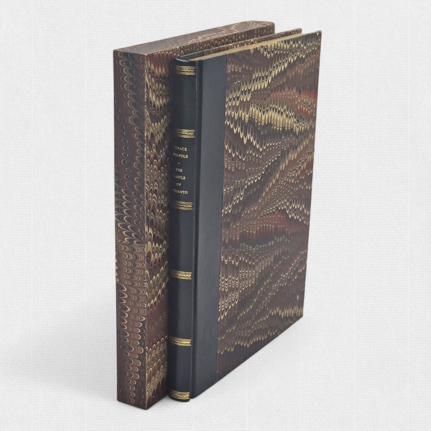 A luxurious 2022 Rambler Press edition of The Castle of Otranto by Horace Walpole, limited to 25 hand-numbered copies. The octavo book, printed on Century Laid cotton paper with watermarks in Monotype Bell typeface, features a half-leather binding with hand-marbled paper sides, gilded edges, and a custom slipcase. The cover evokes the eerie Gothic atmosphere of the 1764 novel, with shadowy castle motifs and intricate detailing, reflecting its status as the cornerstone of the Gothic genre.