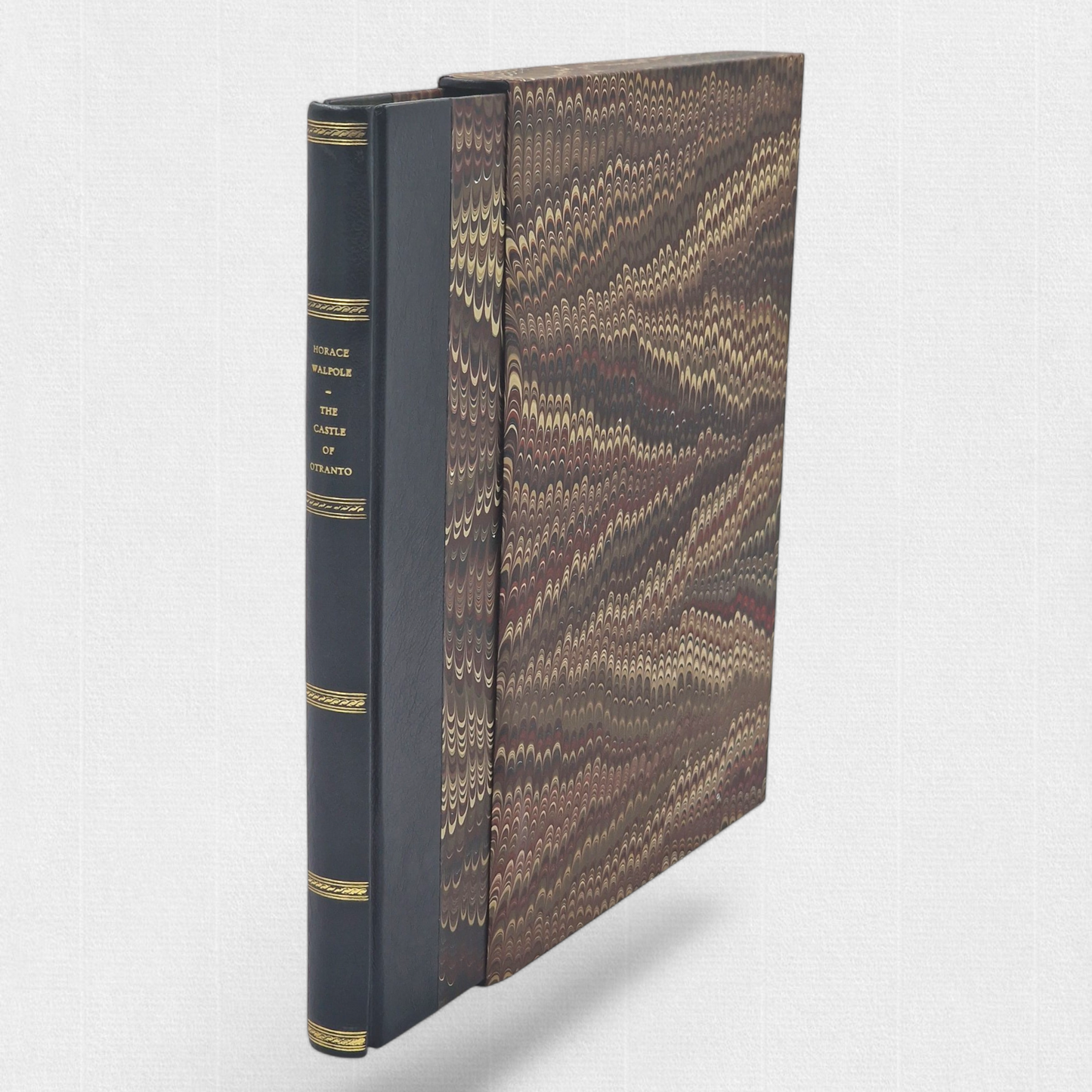A luxurious 2022 Rambler Press edition of The Castle of Otranto by Horace Walpole, limited to 25 hand-numbered copies. The octavo book, printed on Century Laid cotton paper with watermarks in Monotype Bell typeface, features a half-leather binding with hand-marbled paper sides, gilded edges, and a custom slipcase. The cover evokes the eerie Gothic atmosphere of the 1764 novel, with shadowy castle motifs and intricate detailing, reflecting its status as the cornerstone of the Gothic genre.
