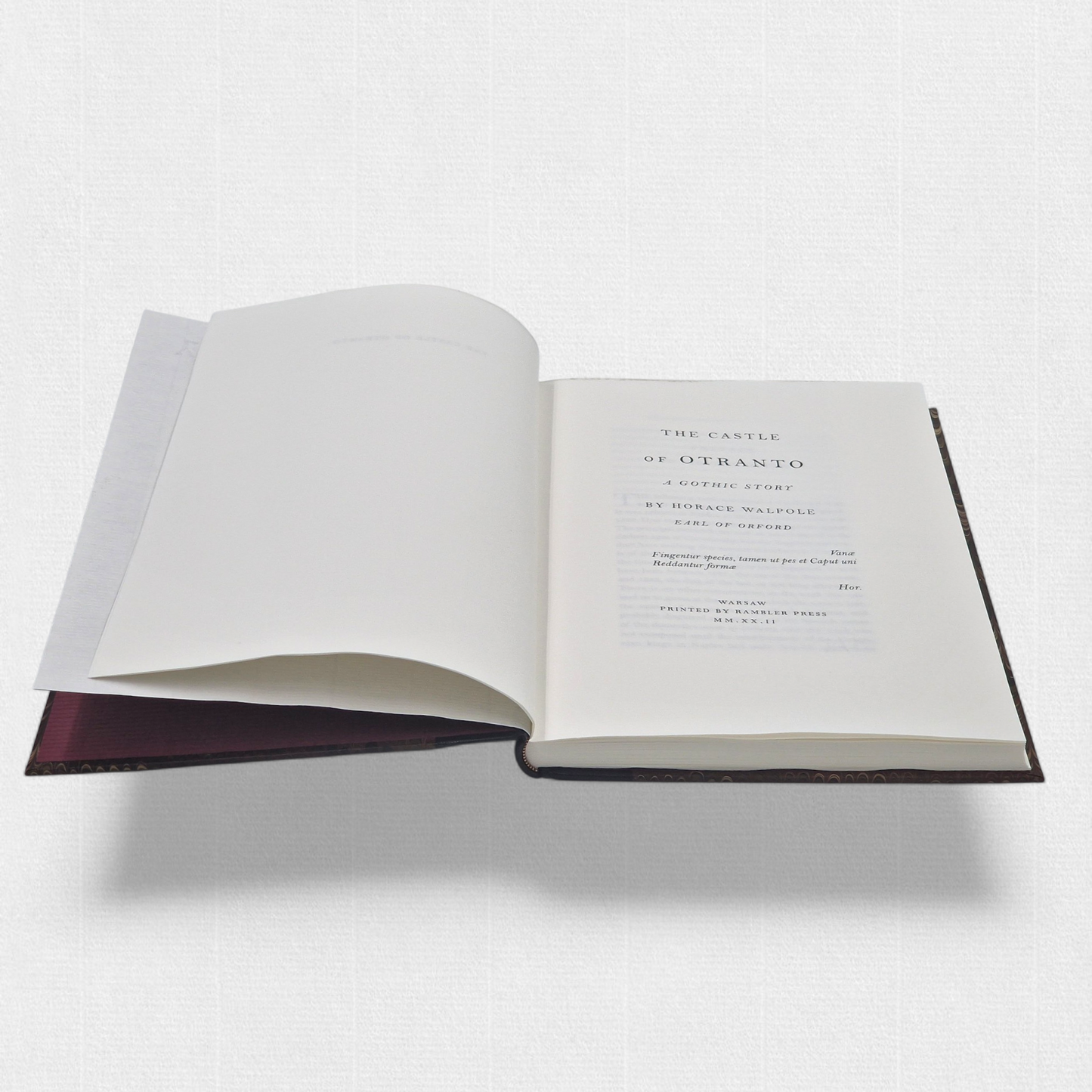 A luxurious 2022 Rambler Press edition of The Castle of Otranto by Horace Walpole, limited to 25 hand-numbered copies. The octavo book, printed on Century Laid cotton paper with watermarks in Monotype Bell typeface, features a half-leather binding with hand-marbled paper sides, gilded edges, and a custom slipcase. The cover evokes the eerie Gothic atmosphere of the 1764 novel, with shadowy castle motifs and intricate detailing, reflecting its status as the cornerstone of the Gothic genre.