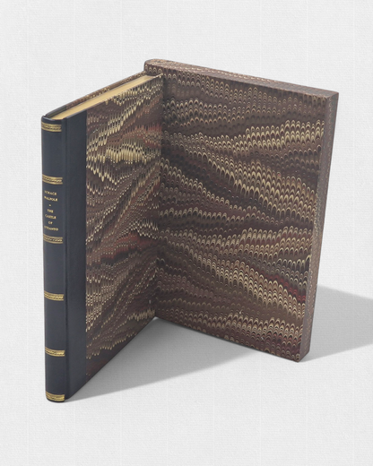 A luxurious 2022 Rambler Press edition of The Castle of Otranto by Horace Walpole, limited to 25 hand-numbered copies. The octavo book, printed on Century Laid cotton paper with watermarks in Monotype Bell typeface, features a half-leather binding with hand-marbled paper sides, gilded edges, and a custom slipcase. The cover evokes the eerie Gothic atmosphere of the 1764 novel, with shadowy castle motifs and intricate detailing, reflecting its status as the cornerstone of the Gothic genre.